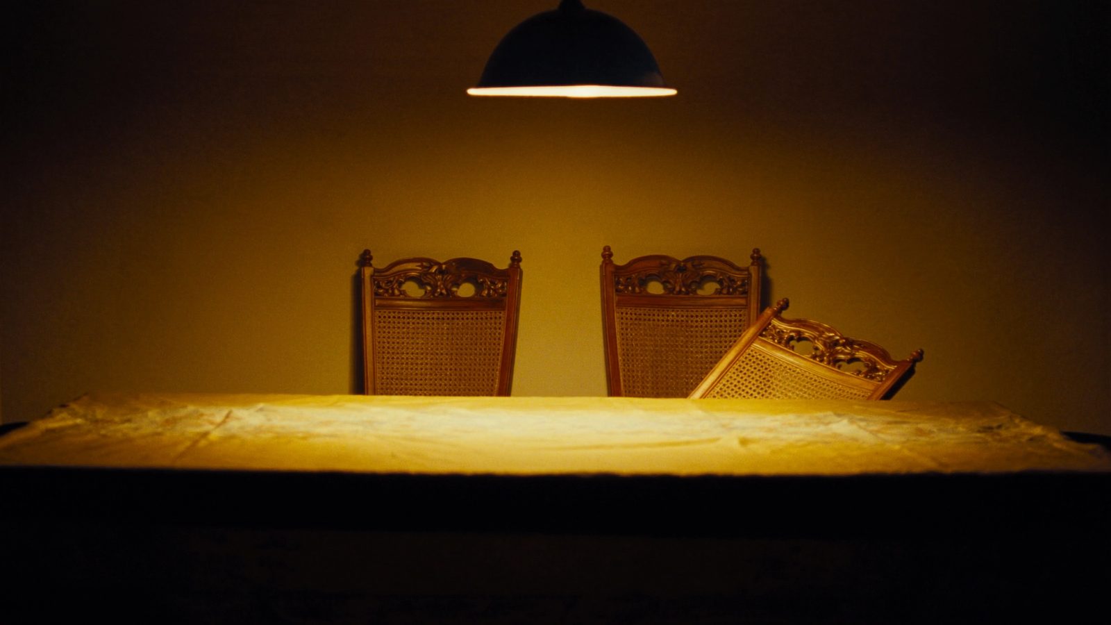 Una mesa de comedor vacía, con las sillas alrededor y una apartada.