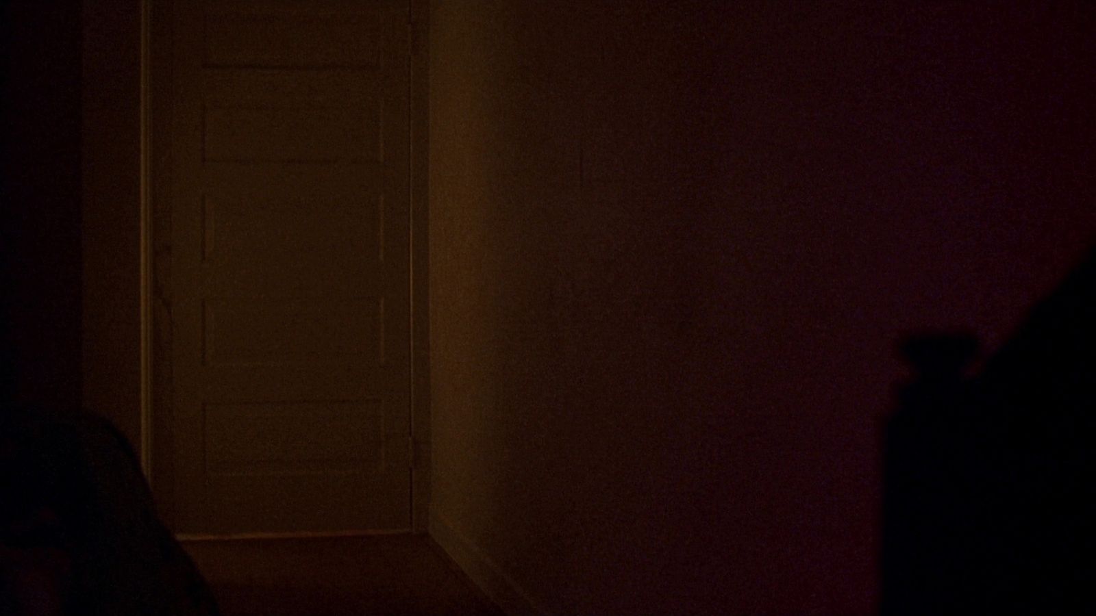 Un pasillo en penumbra: la puerta entreabierta de un cuarto infantil y la luz cálida de una lamparita.